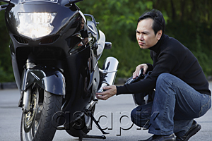 AsiaPix - Man looking at motorcycle
