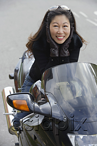 AsiaPix - Woman sitting on motorcycle, hands to face, smiling at camera