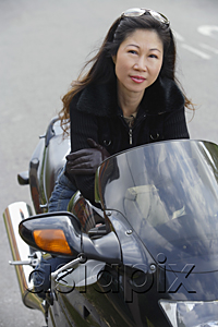 AsiaPix - Mature woman sitting on motorcycle, smiling at camera
