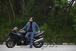 AsiaPix - Mature man leaning against motorcycle, wearing sunglasses