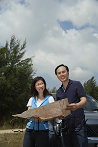 AsiaPix - Woman and man standing by car, reading map, looking at camera