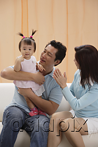 AsiaPix - Mother and Father with baby girl, sitting on couch, happy