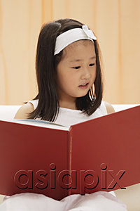 AsiaPix - young female child reading book, sitting on couch