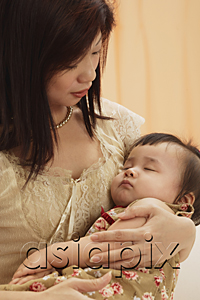 AsiaPix - mother holding baby girl in arms, baby sleeping, mother looking at baby