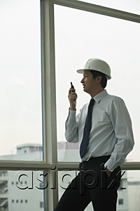 AsiaPix - man wearing hard hat, talking into walkie talkie and looking out window