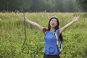 AsiaPix - Woman hiking in nature, raising arms to the sky and smiling