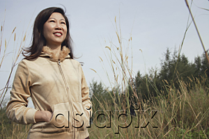 AsiaPix - Woman standing in tall grass, nature, looking up to sky