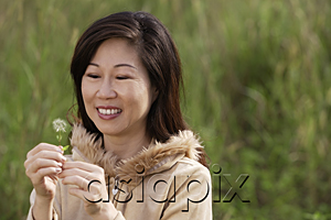 AsiaPix - woman holding flower, standing in tall grass, outdoors