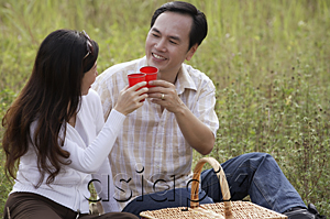 AsiaPix - Man and woman outdoors having picnic, toasting glasses and looking at each other