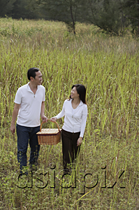 AsiaPix - Man and woman walking through nature carrying picnic basket