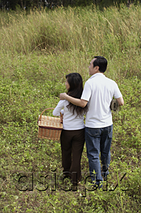 AsiaPix - Man and woman walking in nature, holding picnic basket, back to camera