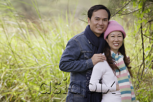 AsiaPix - Man and woman wearing hat and scarves, standing outdoors in nature, smiling at camera