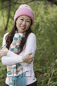 AsiaPix - Woman outdoors wearing hat and scarf hugging herself, cold