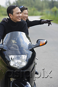 AsiaPix - Man and woman riding motorcycle, woman pointing in direction