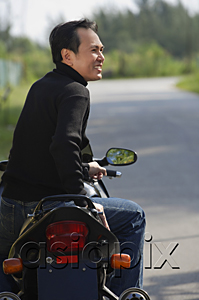 AsiaPix - Man sitting on Motorcycle, looking away