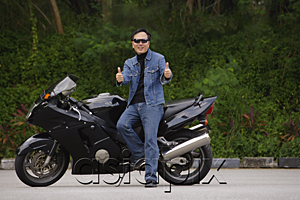 AsiaPix - Man sitting on motorcycle, giving thumbs up
