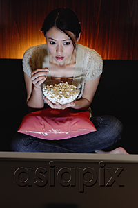 AsiaPix - Young woman eating popcorn and watching TV