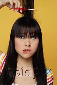 AsiaPix - Young woman cutting hair, having doubts