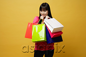 AsiaPix - Young woman holding shopping bags close to herself, smiling