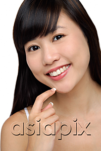 AsiaPix - Young woman smiling, finger to chin, portrait