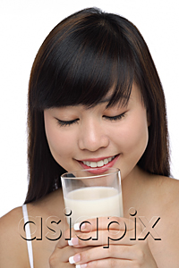 AsiaPix - Young woman holding glass of milk, eyes closed