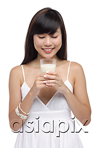 AsiaPix - Young woman holding glass of milk, looking down at milk