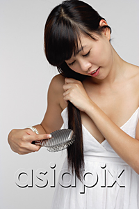 AsiaPix - Young woman wearing white dress and brushing hair