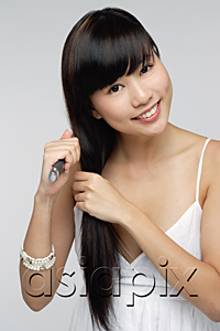 AsiaPix - Young woman wearing white dress, brushing hair and smiling