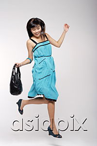 AsiaPix - Young woman wearing blue dress, holding purse and jumping