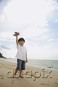 AsiaPix - young boy on beach flying wooden airplane