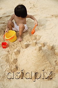 AsiaPix - Young boy on beach building sand castle