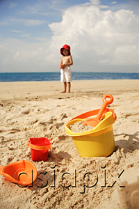 AsiaPix - Young boy on beach, beach bucket and toys in foreground