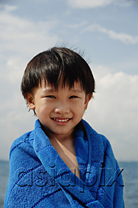 AsiaPix - Young boy on beach wrapped in blue towel