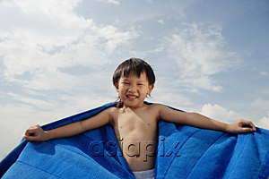 AsiaPix - Young boy on beach with blue towel flying behind him