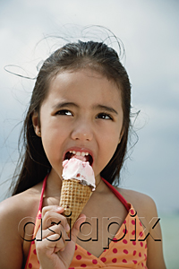 AsiaPix - Young girl on beach eating an ice cream cone