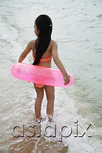 AsiaPix - Young girl on beach wearing bikini and carrying pink inner tube