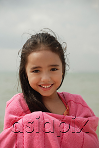 AsiaPix - Young girl on beach wrapped in pink towel, smiling