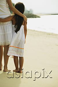 AsiaPix - Mother and daughter standing on beach, arms around each other, rear view