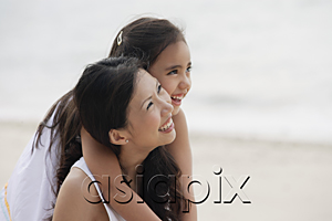 AsiaPix - Mother and daughter on beach, daughter hugging mother from behind