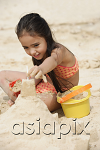 AsiaPix - Young girl building sand castle on beach