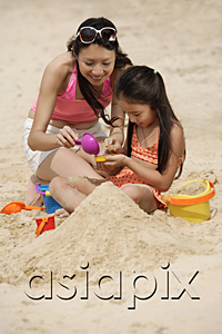 AsiaPix - Mother and daughter building sand castle on beach