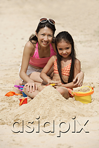 AsiaPix - Mother and daughter sitting in sand on beach, building sand castle