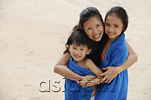 AsiaPix - Mother, son and daughter on beach, kids wrapped in blue towel, mother hugging children