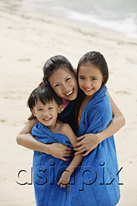 AsiaPix - Mother on beach with son and daughter, mother hugging children and wrapping them in blue towel