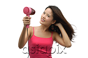 AsiaPix - Young woman blow drying hair and looking at camera