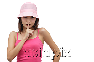 AsiaPix - Young woman wearing pink hat with finger to mouth, be quiet please