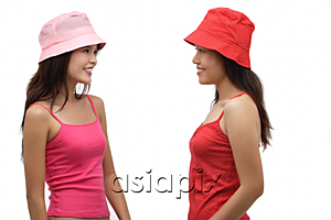 AsiaPix - Two young women wearing pink and red hats, looking at each other