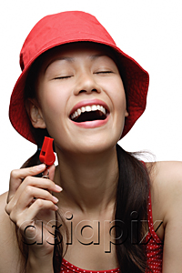 AsiaPix - Young woman wearing red hat and holding whistle, laughing