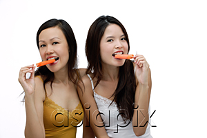 AsiaPix - Two young women biting into Popsicle, looking at camera