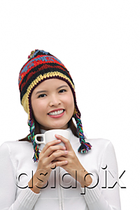 AsiaPix - Young woman wearing winter hat, holding mug of hot chocolate